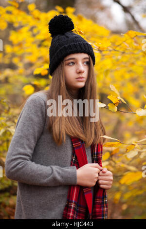 Bella ragazza adolescente indossando cappello di lana con colori autunnali in background cercando la distanza Foto Stock