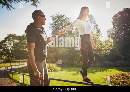 Donna che mantiene le mani con personal trainer camminando sul recinto del parco Foto Stock