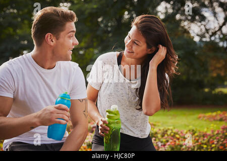 L uomo e la donna la formazione nel parco, chiacchierando durante una pausa di acqua Foto Stock