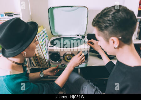 Sulla spalla vista di due giovani donne a giocare su vinile giradischi vintage Foto Stock