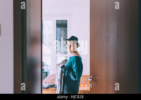 Porta Ritratto di giovane donna che indossa trilby in piedi in camera da letto Foto Stock