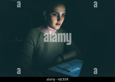 Tasto basso Ritratto di giovane donna staring al laptop Foto Stock