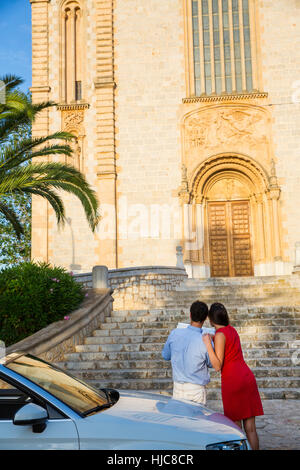 Vista posteriore della giovane coppia con convertibili guardando la mappa, Calvia, Maiorca, SPAGNA Foto Stock