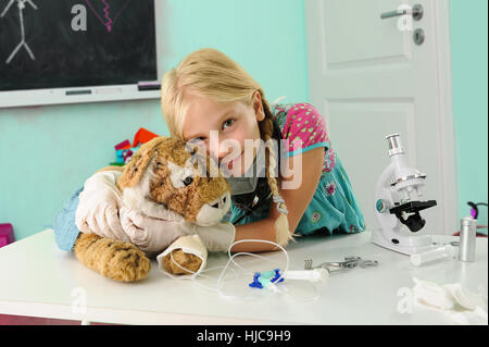 Ritratto di ragazza fingendo di essere vet abbracciando toy tiger con gocciolamento endovenoso Foto Stock