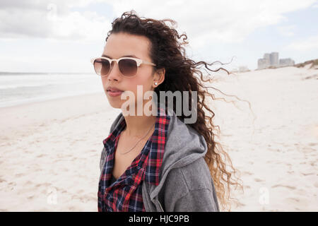 Giovane donna in occhiali da sole a passeggiare da solo sulla spiaggia di Ventoso, Western Cape, Sud Africa Foto Stock