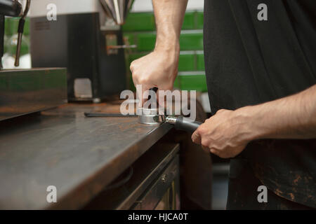 Barista maschio con le mani in mano la preparazione di macchina per caffè nella caffetteria Foto Stock