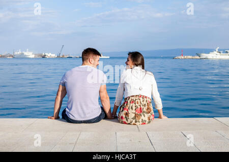 Vista posteriore del giovane seduto sul porto, Split, Dalmazia, Croazia Foto Stock