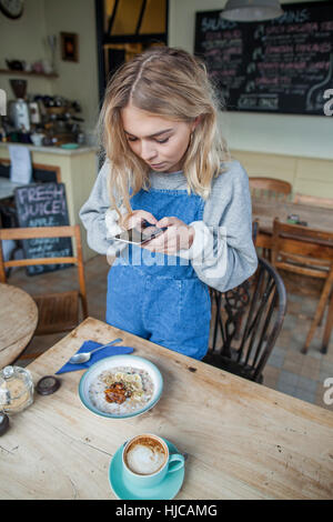 Giovane donna in cafe, utilizza lo smartphone Foto Stock