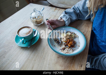 Giovane donna in cafe, mangiare muesli, metà sezione Foto Stock