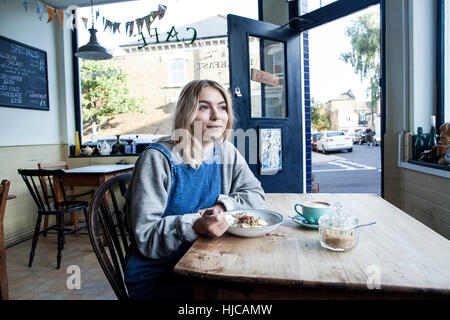 Giovane donna in cafe, mangiare muesli Foto Stock