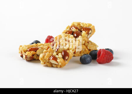 Due snack bar con mandorle e noci e frutti di bosco su sfondo bianco Foto Stock
