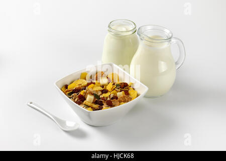 Ciotola di fiocchi di avena con la brocca del latte e bicchiere di yogurt bianco su off-sfondo bianco con ombre Foto Stock