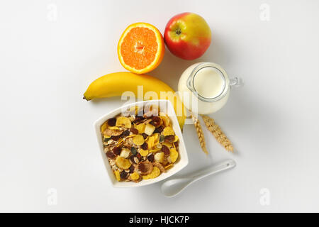 Ciotola di fiocchi di avena, brocca del latte e frutta su off-sfondo bianco con ombre Foto Stock