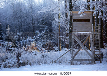 Un cacciatore di nascondiglio per la stagione di ripresa è coperto di neve su una bella giornata invernale e nel sud della Baviera, Germania Foto Stock