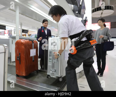 Narita, Giappone. 24 gen 2017. Japan Airlines (JAL) personale di terra che indossa una tuta robot ibrido arto Assistive (HAL), sviluppato da Tsukuba University Professor Yoshiyuki Sankai e Cyberdyne dimostra per il trasporto di un bagaglio pesante alla JAL al banco check-in quanto le compagnie aeree hanno iniziato le loro prove in campo di HAL all'Aeroporto Internazionale di Narita a Narita, suburbana Tokyo Martedì, 24 gennaio 2017. Credito: Aflo Co. Ltd./Alamy Live News Foto Stock