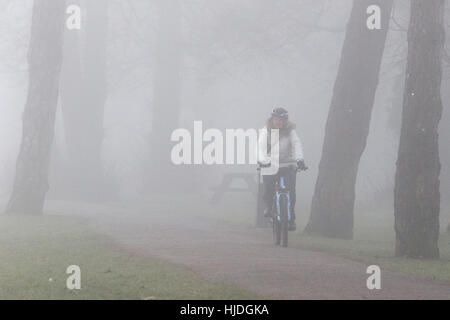 Chippenham, Regno Unito. 25 gennaio 2017. Clima invernale nel Regno Unito. Mentre il freddo nebbioso continua a colpire molte parti del Regno Unito, una donna è ritratta in bicicletta in un parco pubblico a Chippenham, Wiltshire. Crediti: Lynchpics/Alamy Live News Foto Stock