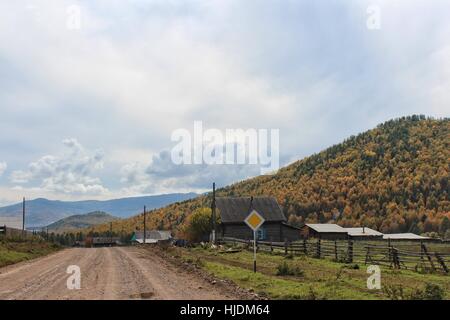 Strada rurale passando attraverso il villaggio di montagna. Autunno paesaggio di montagna. Foto Stock