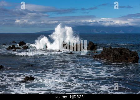 Onde che si infrangono sulle rocce della costa occidentale di Tenerife con l'isola di La Gomera in background. Isole Canarie Spagna Foto Stock