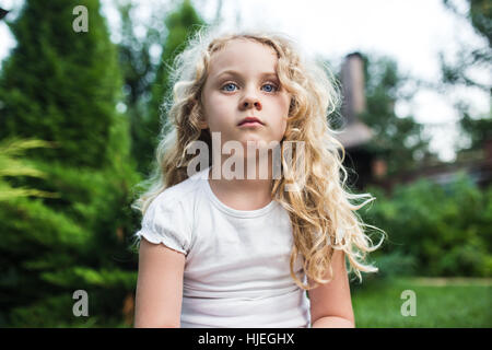 Close-up verticale di pensosa bambina con lunghi capelli biondi Foto Stock