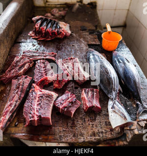 Pezzi freschi di giovani tonni con il sangue per la vendita nel mercato di Darajani su bagnato scrivania in legno, pescato del giorno, Stone Town Zanzibar, Tanzania Africa Foto Stock