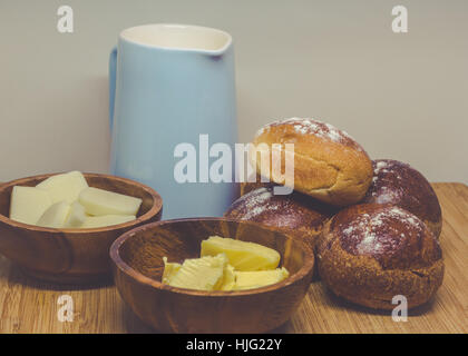 Semplice colazione rustica con ciambelle di pane di burro e di latte su una tavola di legno. Foto Stock