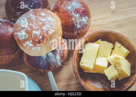 Semplice colazione rustica con ciambelle di pane di burro e di latte su una tavola di legno. Foto Stock