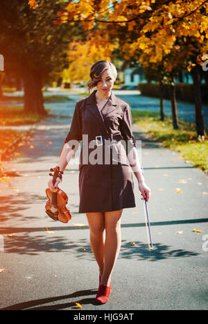 Ritratto di ragazza intelligente con violino sulle mani per esterno in cappotto marrone in autunno. Foto Stock