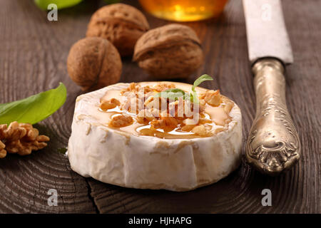 Grigliata di formaggio brie con il miele e i dadi sul vecchio sfondo di legno Foto Stock