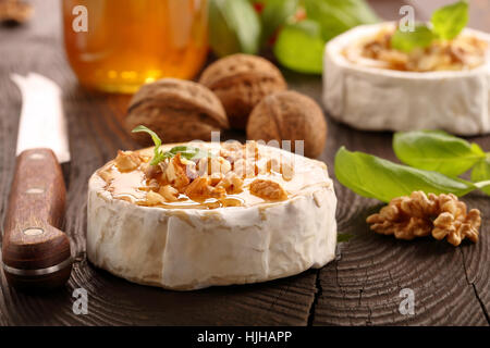 Grigliata di formaggio brie con il miele e i dadi sul vecchio sfondo di legno Foto Stock