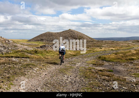 Mountain Biker passando attraverso i motivi di data mining sulle pendici settentrionali del grande Pinseat sopra Arkengarthdale, Yorkshire Dales REGNO UNITO Foto Stock