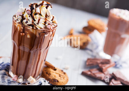 Un confuso il vetro con cioccolata calda, panna montata, marshmallows e biscotti al cioccolato. Foto Stock