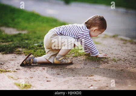 Ragazzo crawl sul terreno in estate park Foto Stock