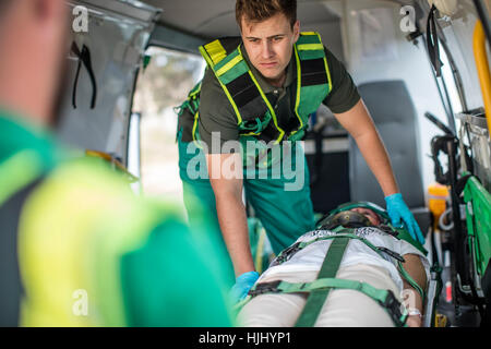 I paramedici vettura in movimento crash vittima sulla barella Foto Stock