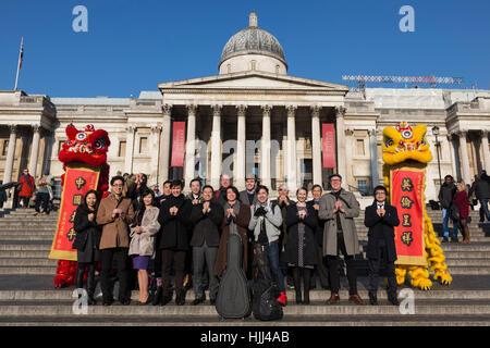 Gli artisti interpreti o esecutori pongono con Lion ballerini da Chinatown sui gradini di Trafalgar Square di fronte alla Galleria Nazionale davanti a questo weekend di "Anno del Gallo' Capodanno cinese a Londra, Regno Unito. Foto Stock