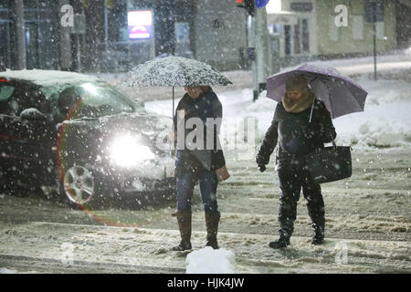 VELIKA Gorica, Croazia - gennaio 13th, 2017 : due donne con ombrelloni attraversando la strada nel traffico durante una forte nevicata nel Velika Gorica, Croazia. Foto Stock