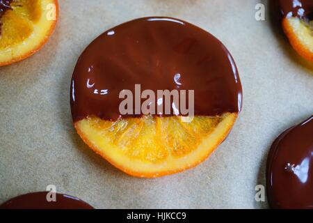 Rendendo i canditi di fettine di arancia immersi nel cioccolato fondente Foto Stock