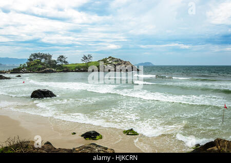 Spiaggia con alcune rocce sulla sabbia e un mini isola sullo sfondo Foto Stock