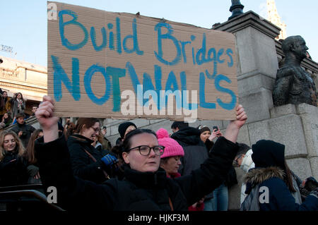 Le donne di anti-Trump marzo, Londra. Una donna in Trafalgar Square detiene un cartello che dice "costruire ponti e non muri". Foto Stock