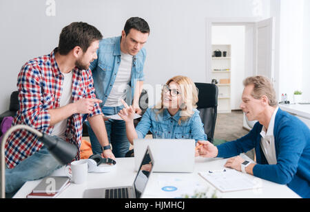 Attraente giovane donna puntando al suo collega Foto Stock