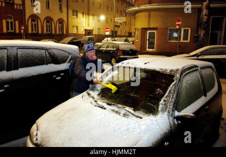 Uomo di pulizia auto neve il cofano con il raschiatore Foto Stock