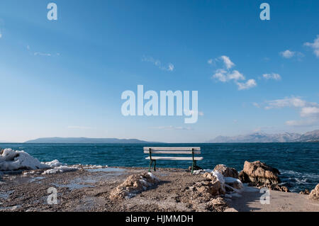 Banco vuoto con vista mare e neve intorno Foto Stock