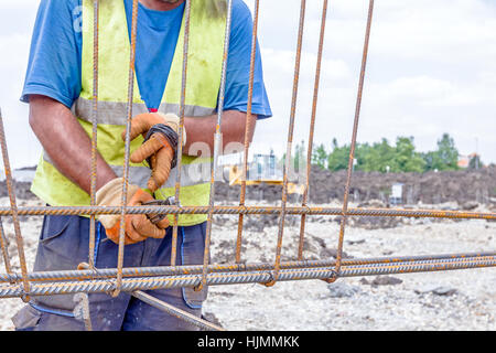 Lavoratore è la legatura rebar per effettuare un nuovo basamento costruito il telaio. Il legame del telaio in calcestruzzo Foto Stock