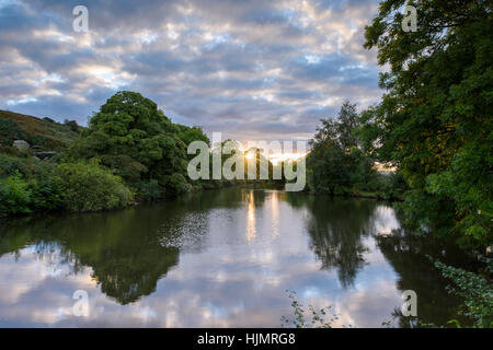 Suggestiva scena con sky riflessi nell'acqua di Ilkley Tarn su una tarda serata estiva al tramonto - West Yorkshire, Inghilterra. Foto Stock