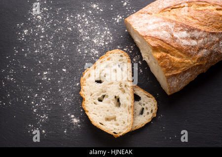 Una pagnotta di pane di grano e le fette su un piatto di ardesia Foto Stock