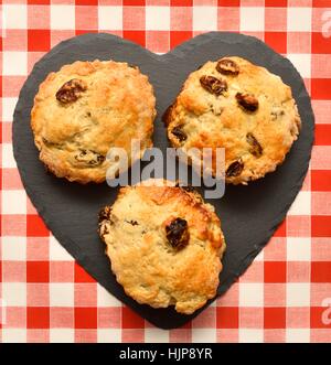 3 scones su un cuore pezzo sagomato di ardesia. Foto Stock