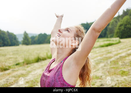 Giovane donna godendo della sua libertà e stirando le braccia in aria Foto Stock