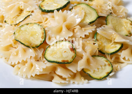 Farfalle di pasta con le fette di zucchine su una piastra bianca orizzontale macro Foto Stock