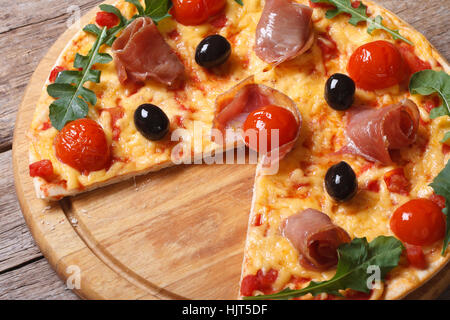 Affettato ??Pizza col prosciutto, pomodori, olive nere e rucola close-up vista da sopra la linea orizzontale Foto Stock