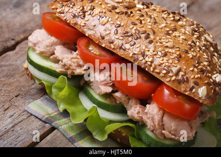 Utile tonno sandwich con lattuga, pomodori, cetrioli close up su un vecchio tavolo orizzontale. Foto Stock