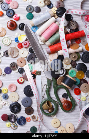 Vecchio forbici, pulsanti, ditale, filettatura su uno sfondo di legno closeup verticale. vista superiore Foto Stock